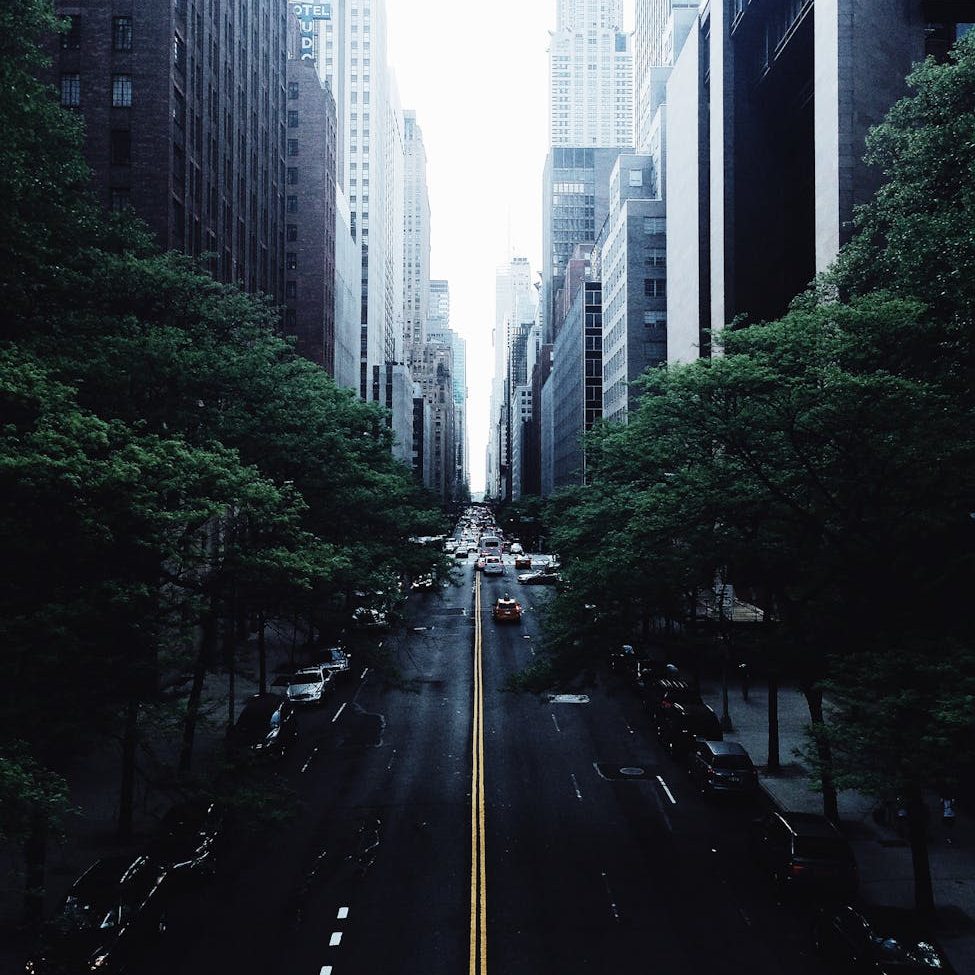white and red car on black concrete narrow road in between high rise buildings photograph